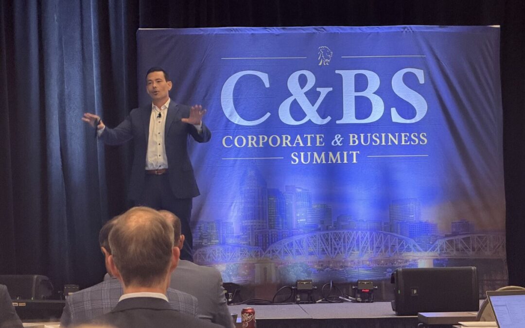 Alex Jones presenting at the Lion Street Corporate & Business Solutions Summit in Nashville, on the C&BS stage with the Nashville bridge and skyline backdrop.